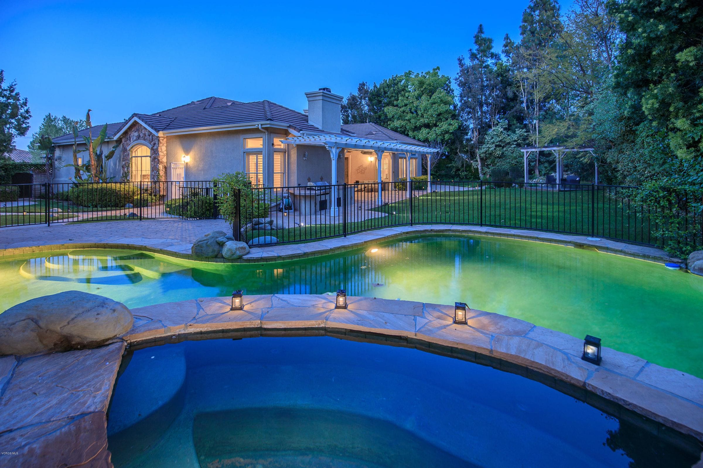 A pool and spa lit at dusk, from one of Connie's listings