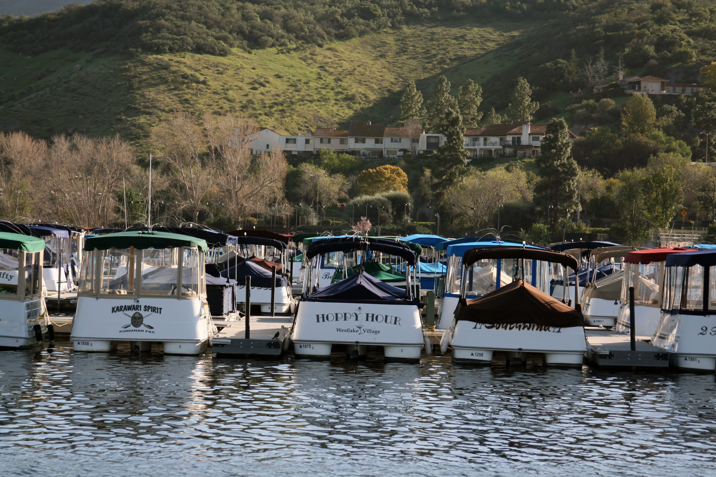 Electric boats docked on Westlake Lake below green hills in Westlake Village
